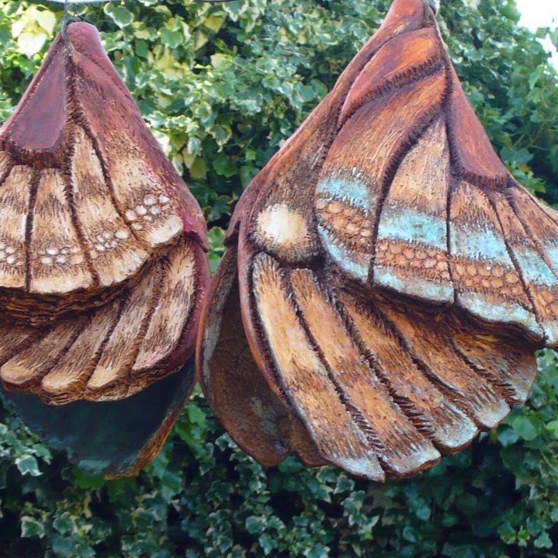 Hanging sculptures based on an unfurling butterfly. Marble resin with rust and verdigris copper with amber red glowing colours emerging