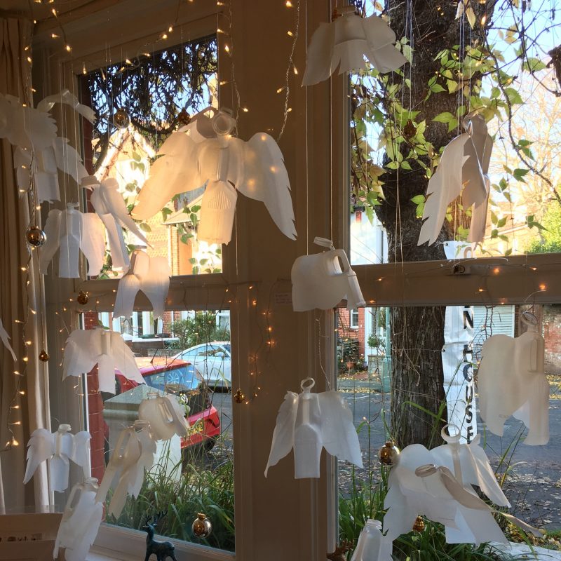 Interior window with angels made from plastic milk cartons hanging 