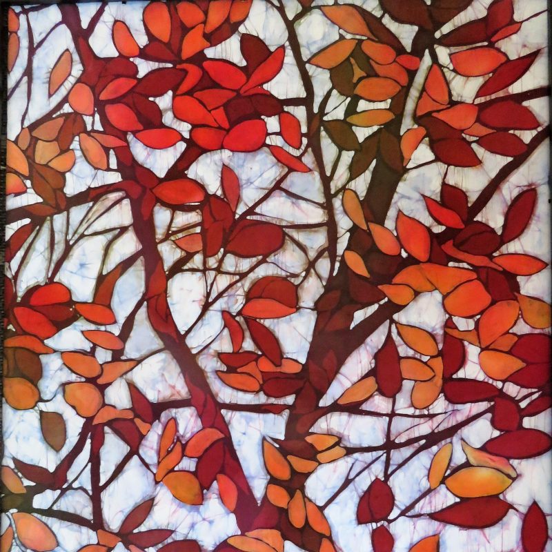 Batik on silk, white background and red, orange, brown leaves dancing on a tree.