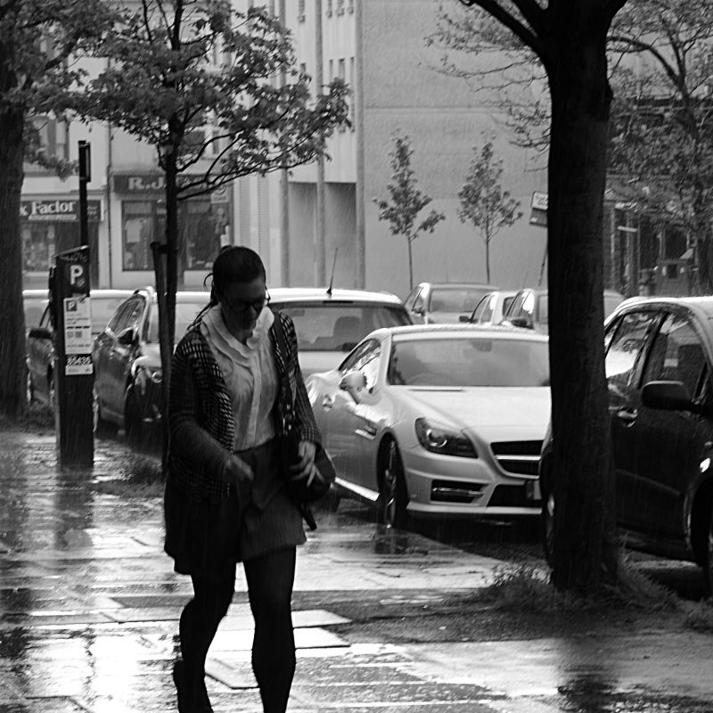 A woman is running along the street in the rain 