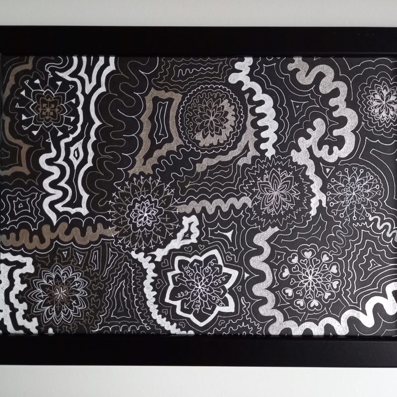 Silver and white A4 landscape drawing using gel pens on black card. Complex interconnected patterns - spirals and cog-like shapes fill the page in between swirly lines.