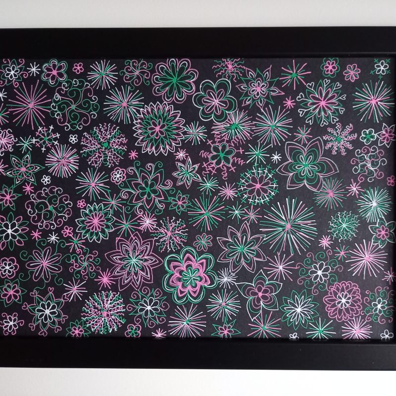 Small pink, green and white firework-like shapes fill the page - A4 landscape drawing using gel pens on black card.