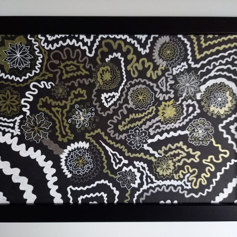 White and gold drawing using gel pens on black card. Complex interconnected patterns - spirals and cog-like shapes fill the page in between swirly lines.