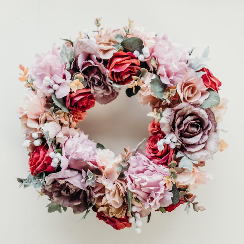 A beautiful, full flower wreath created with a variety of shades of pink roses and hydrangeas with dusty miller green foliage, eucalyptus and white mimosa. This wreath is perfect for hanging on the front door, as a wall hanging or as part of a table centre piece with candles. 
