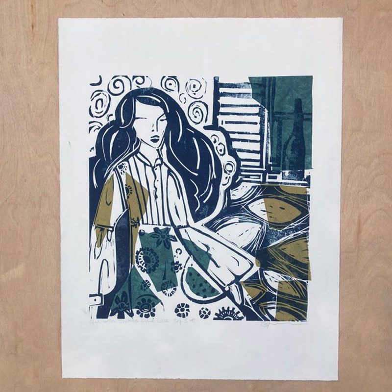 The image is of a long haired woman recling at home, wearing a simple bell sleeve dress by a wall with swirling wall paper & a shuttered window with a wine bottle. The print is very dark navy on an off white ground with evergreen & ochre abstract shadows. 