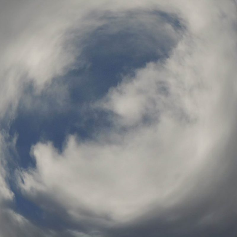 An image of the sky from the ground, the clouds are distorted to resemble a circle 