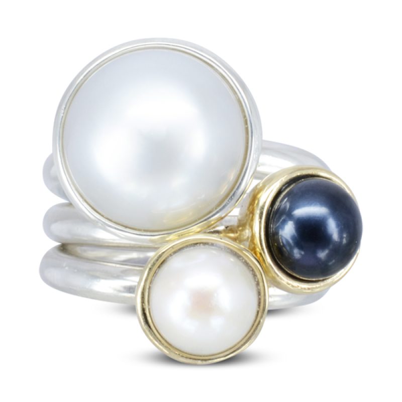 A set of giant pearl stacking rings featuring a 10mm central freshwater round pearl set in silver. Pictured with two 7mm pearl stacking rings with 9ct yellow gold settings.