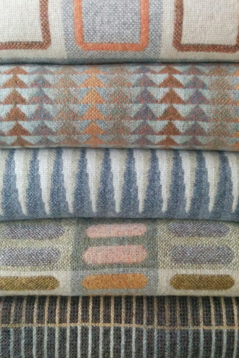 Arange of geometric woven throws in greys and warm tones.