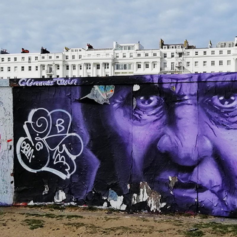 Graffiti of a womans face on a wall with Brighton buildings behind