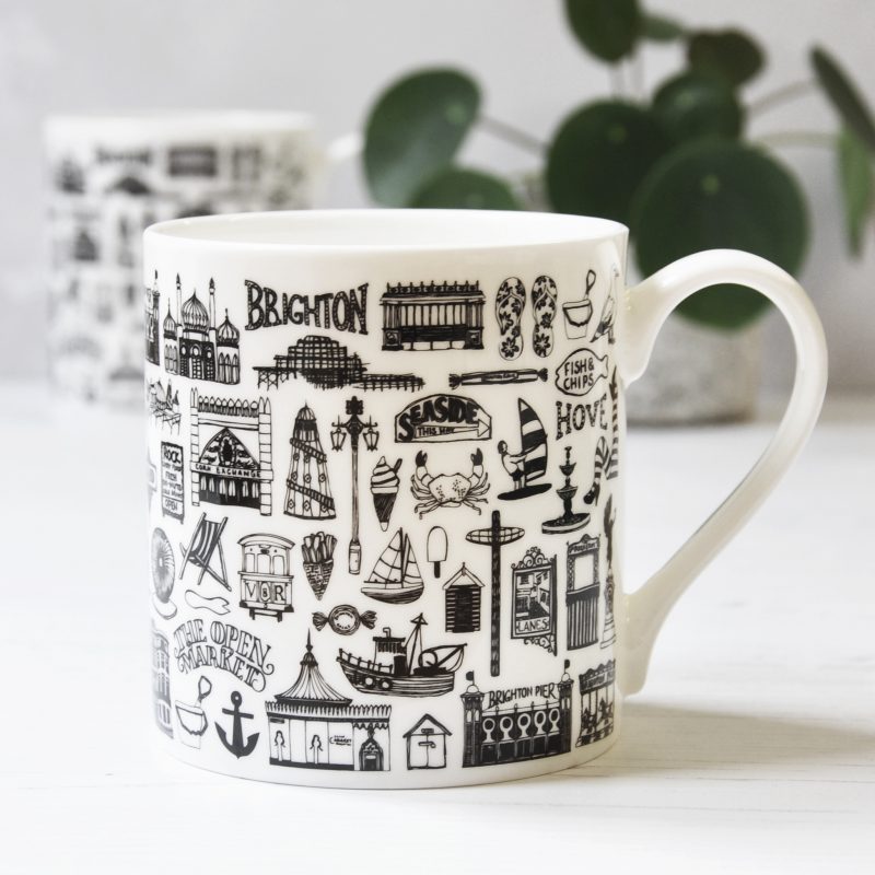 white fine bone china mug decorated with intricate black fine line illustrations of Brighton. 