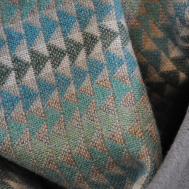 Woven throw, triangle pattern in mint colourway. Shown here in basket.