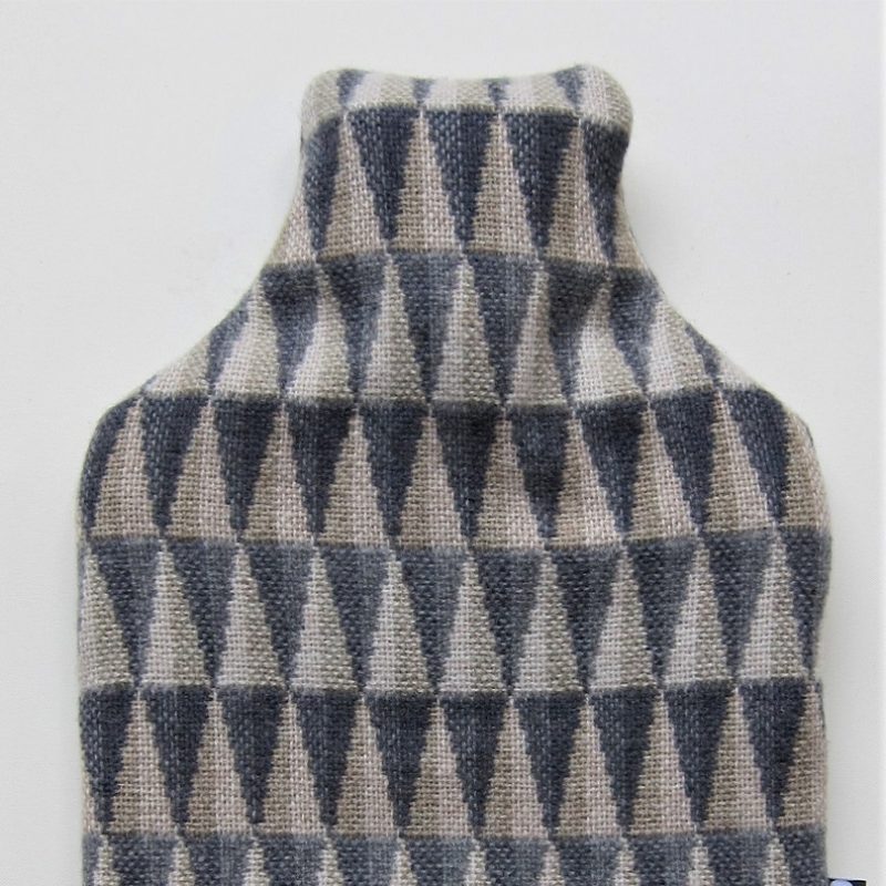 A hot water bottle cover (with bottle inside) in Prism Grey fabric--grey tones, trianular shapes.