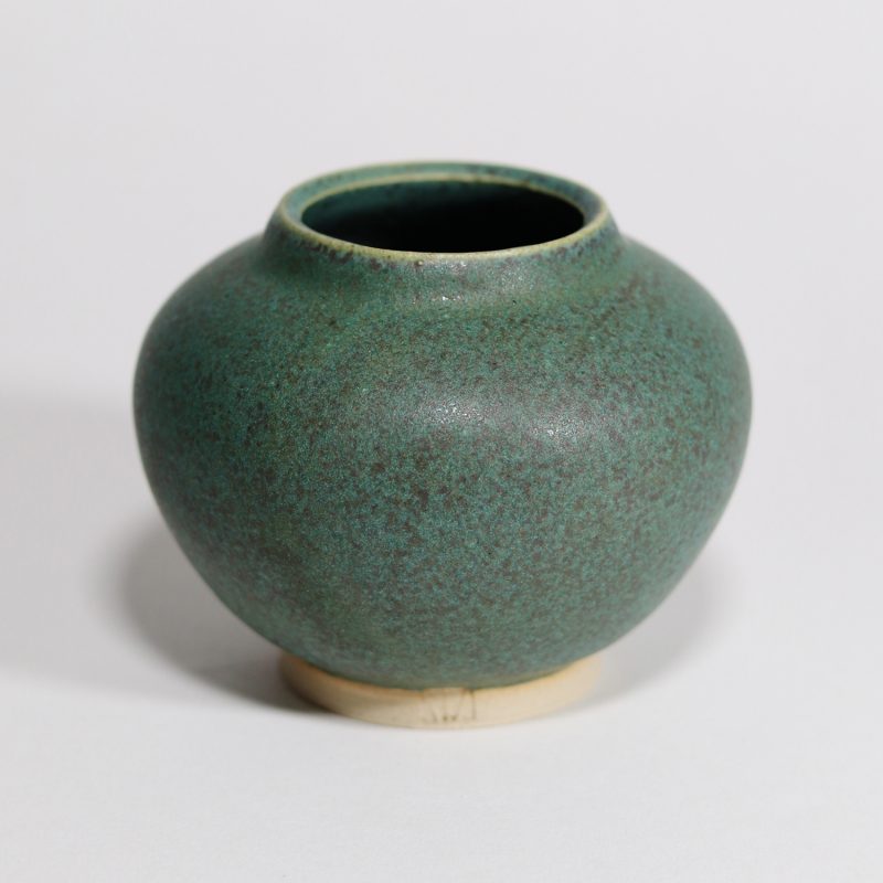 A handmade small bud vase made from a matte green with slight black speckle glaze