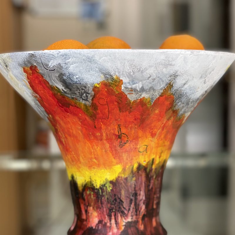 A vessel made in air dry clay depicting bright orange/yellow volcanic explosion