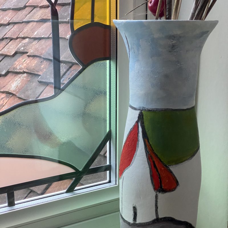 a vase made in air dry clay depicting an abstract image of a house and tree.