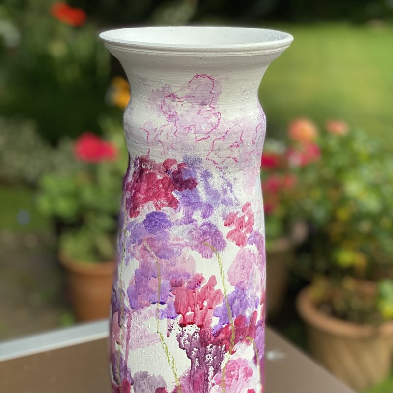 A ceramic vase using air dry clay and painted with an array of abstract sweet peas in pinks 