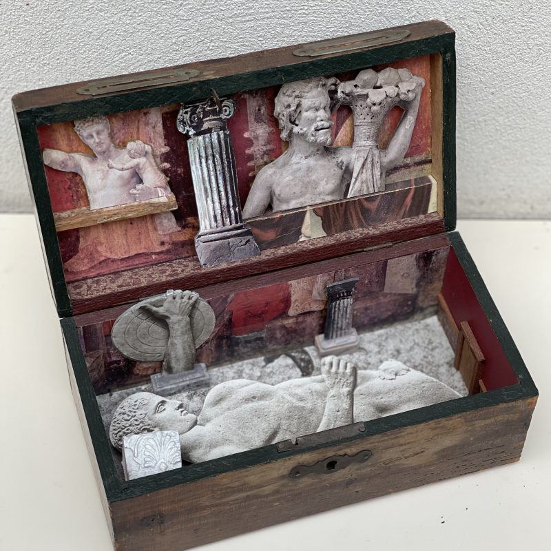 A wooden box with collages and objects inside