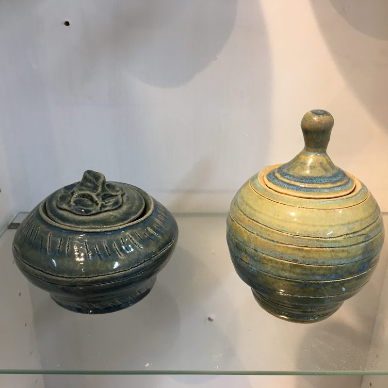 Two small ornamental jars displayed in a glass cabinet