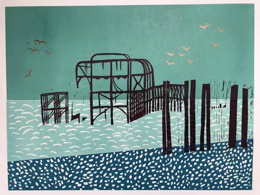 A print of the black skeleton of the west pier on a background of teal and turquoise sky, sea and pebbly beach.  Gold seagulls in the sky. 