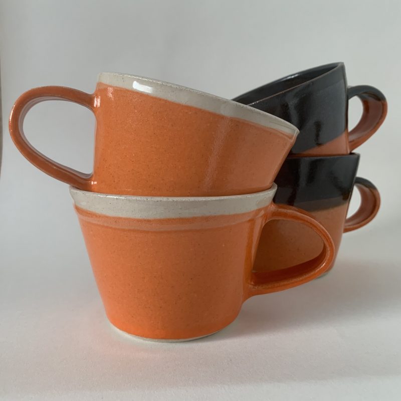 handthrown stoneware ceramic mugs with a bright orange glossy glaze, with either a dark or natural glossy finished inside
