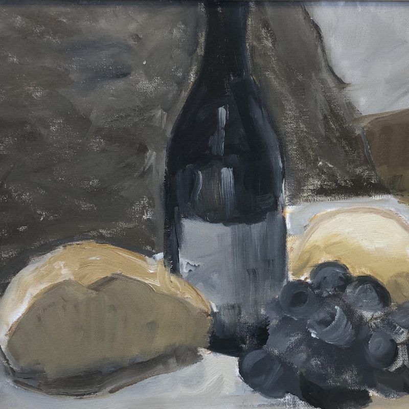 Still Life: bottle of wine, crusty bread, black grapes and a lemon on a pale tablecloth against a dark background.
