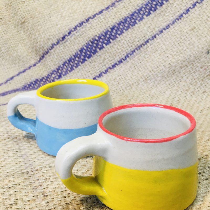 Two retro-inspired coffee mugs featuring primary colours. Thrown stoneware with dipped rim and slip painted bases.