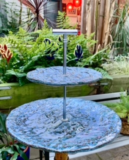 A blue ceramic cakestand in a garden