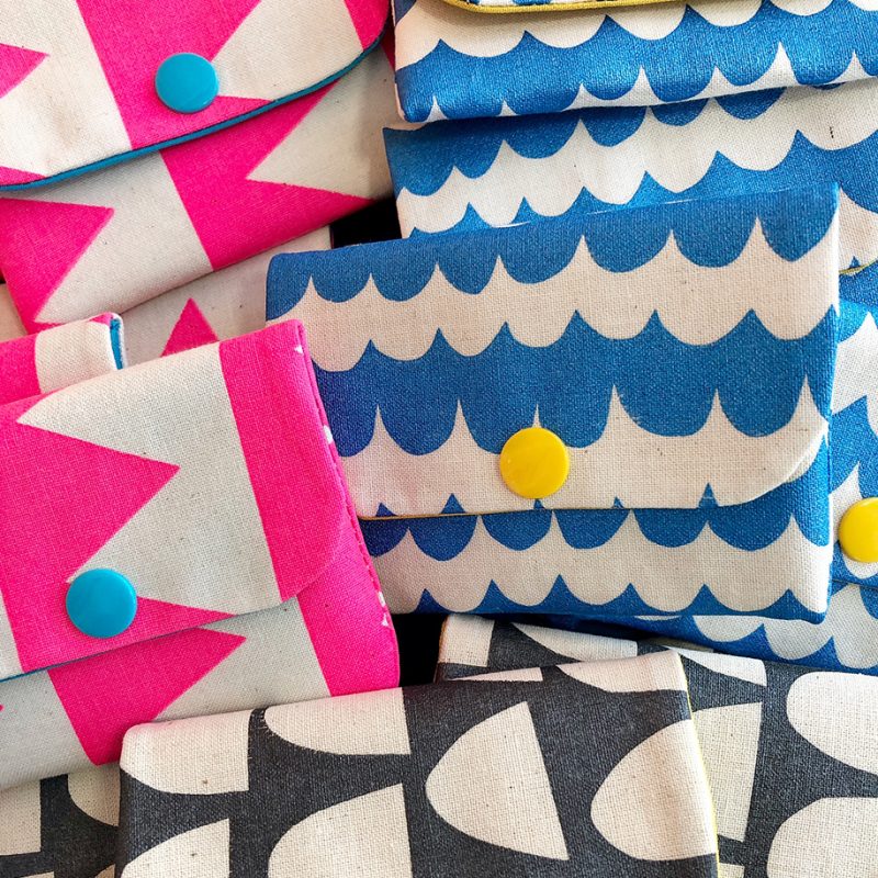  Several brightly coloured little hand screen printed card wallets with neon pink triangle, blue wave and black and white  semi circle patterns