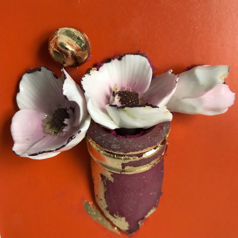 A small picture in relief of a glass vase with recycled china flowers. 