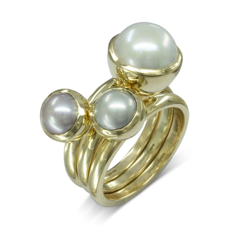A set of Pearl Stacking Rings featuring two 7.5mm and one 10mm round Freshwater pearls set in 9ct yellow gold cup settings. The bands are 3mm wide.