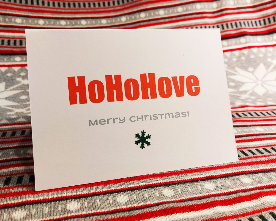 Typographic Xmas card with the words Ho Ho Hove - Merry Christmas! in red with a snowflake motif.
