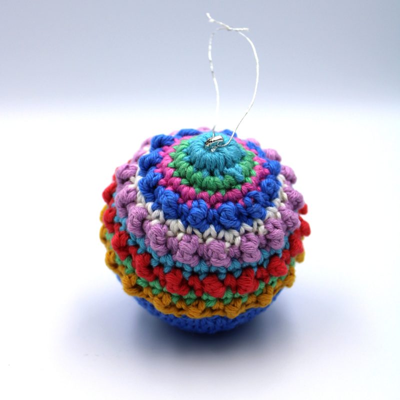 A crochet Christmas tree bauble in bright tones.