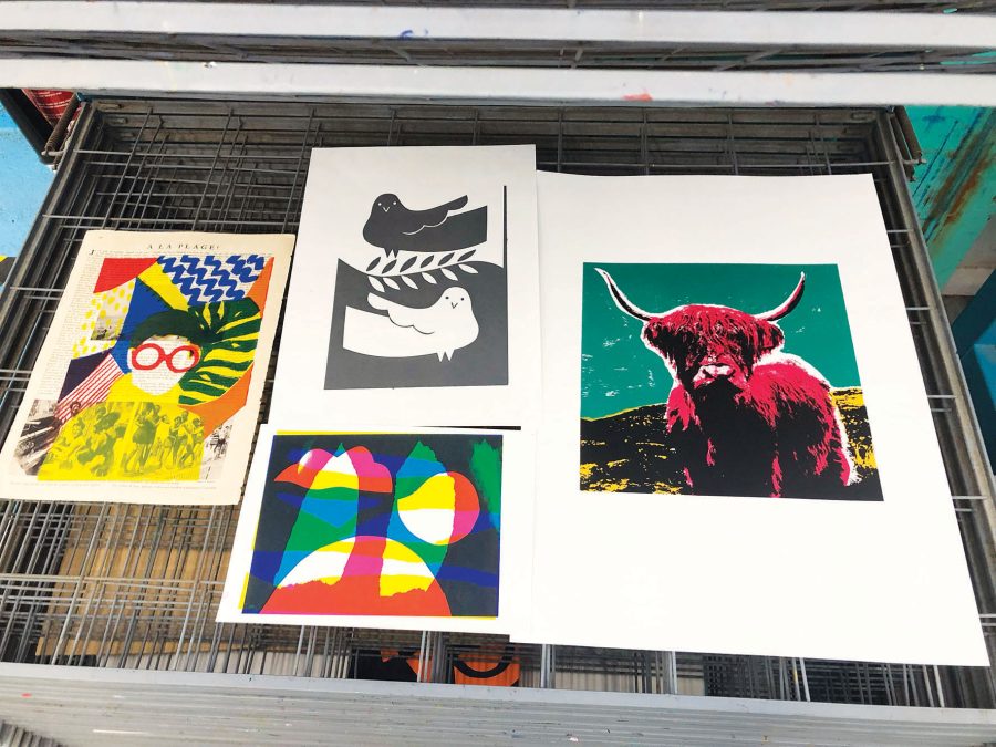 A drying rack with 4 screenprints by different artists laid out flat