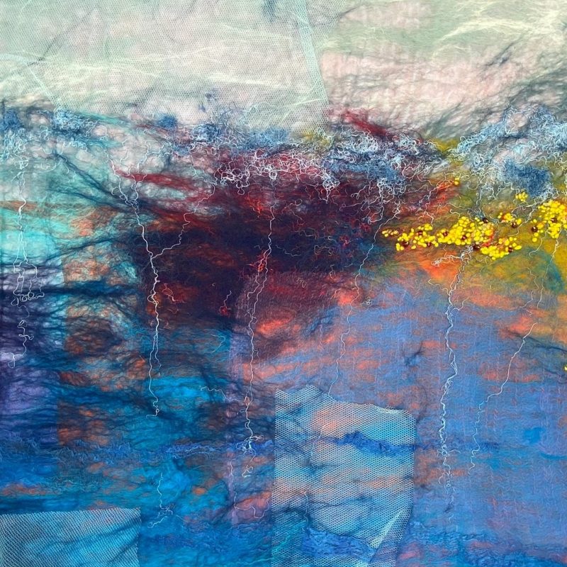 In felt the waters edge is reflecting the bank and sun from the sky. An abstract felt art capturing water reflection in pinks, blues and yellows.