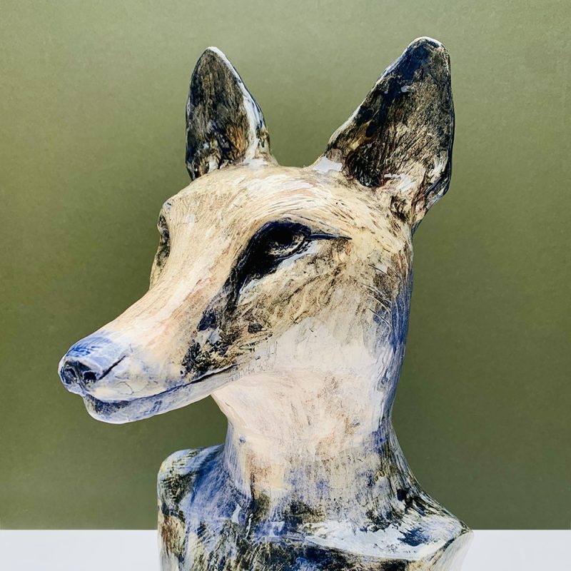 A ceramic sculpture of a fox head with human shoulders finished with cobalt oxide and a glossy transparentglaze.