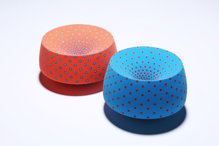 2 ceramic vessels, one blue with red spots, one red with blue spots, both create an optical illusion visual effect