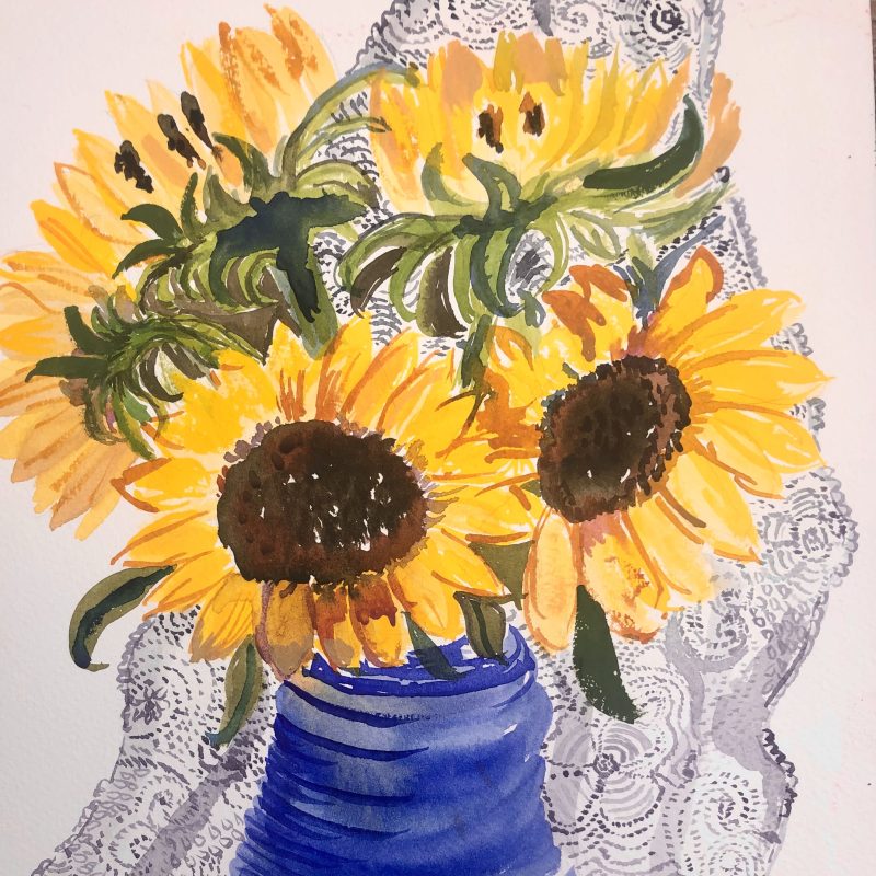 Sunflowers in a blue vase against a background of old lace