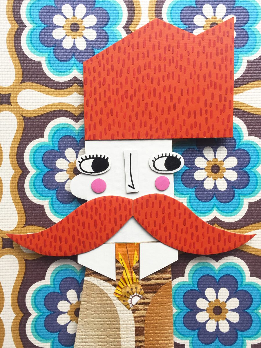 A colourful boy with big orange hair and moustache made from painted cardboard mounted on bright floral vintage wallpaper