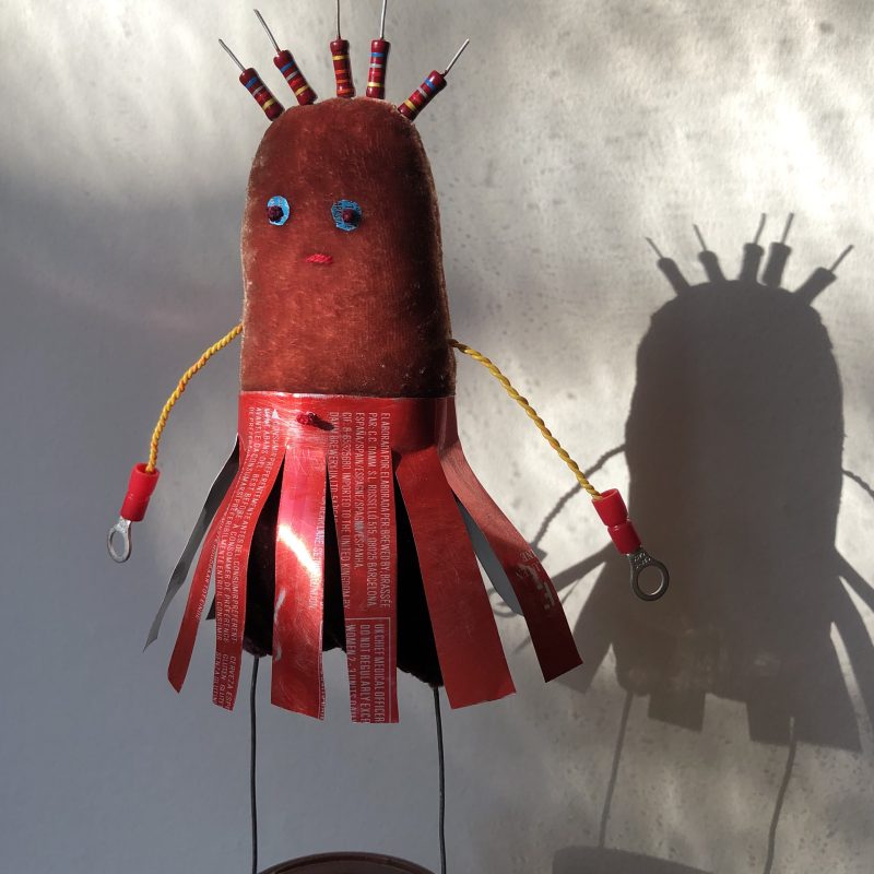 An oval creature in deep red velvet with a red cut tin skirt, wire arms and hair