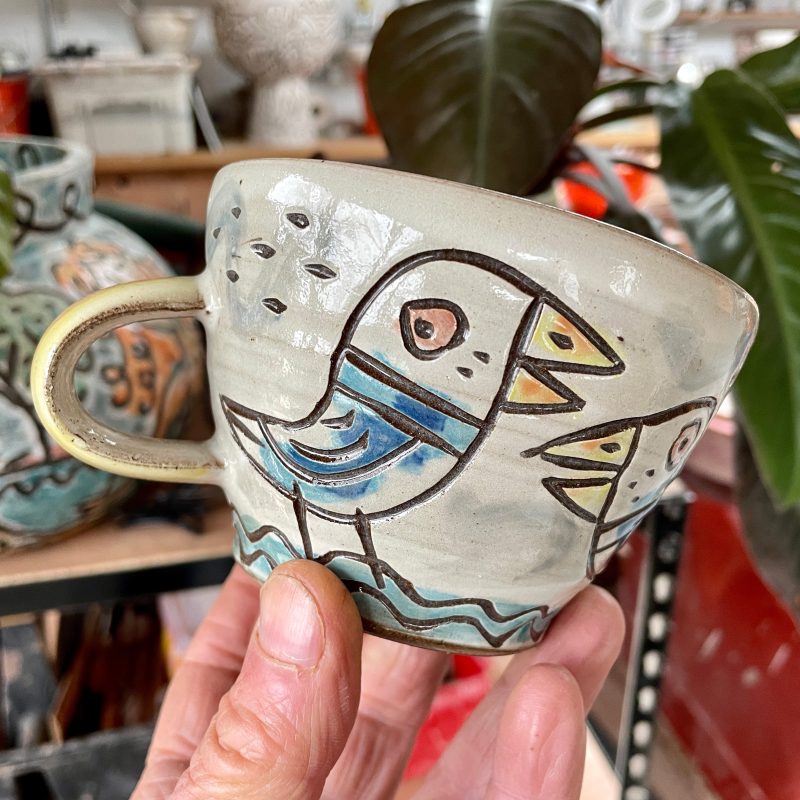 Round coffeee mug with seabird painted and carved decoration.