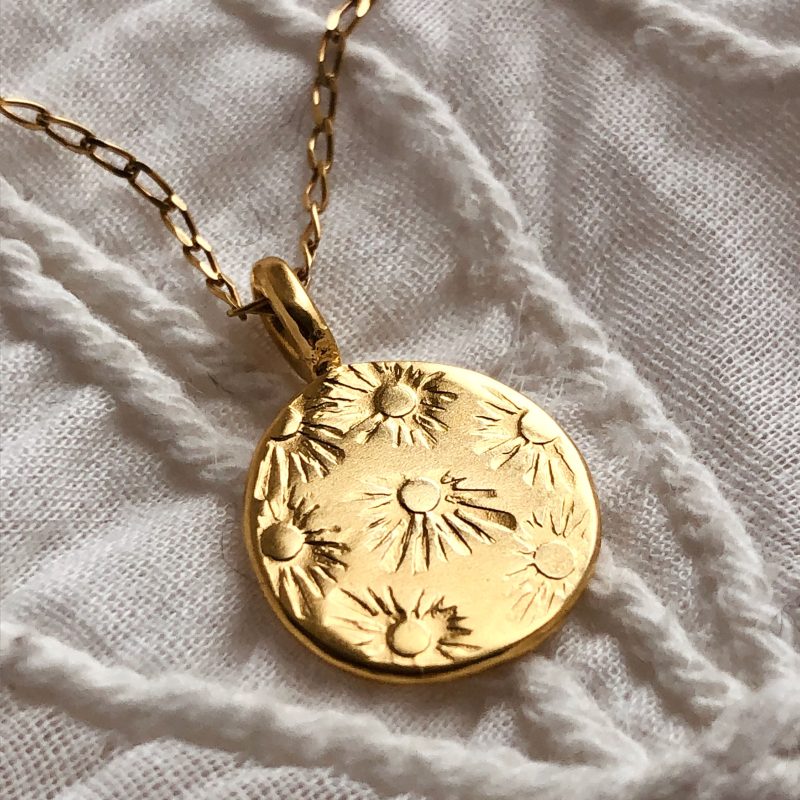 Handcrafted sunbeam embossed coin pendant.