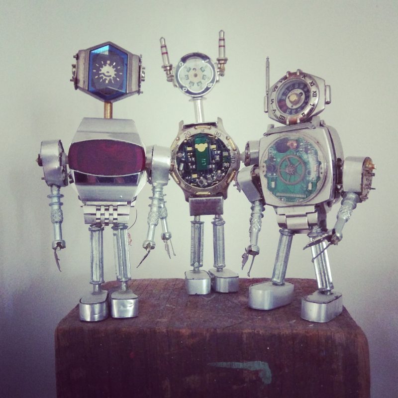3 different metal sculptures of robots made from vintage watch parts