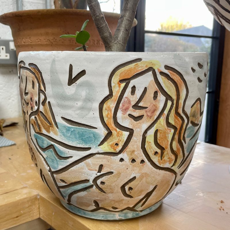 Planter with swimming nudes painted around the pot.