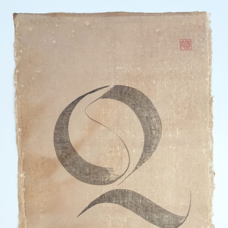 A capital letter Q written on naturally dyed handmade paper. Written with sumi stick ink.