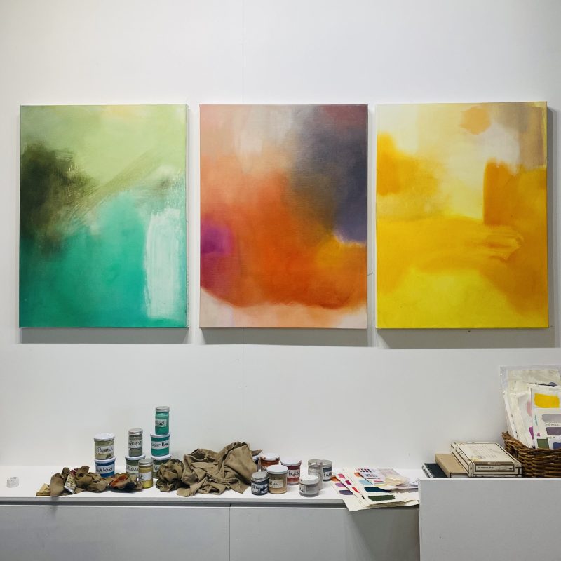 three colourful abstract paintings in artists studio  