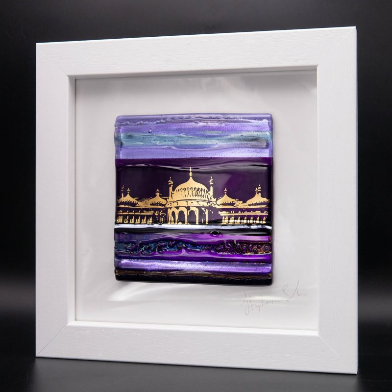 A beautifully textured fused tile in of purple glass with an image of Brighton Royal Pavilion in shimmering gold.  Framed in a contemporary white wooden frame 