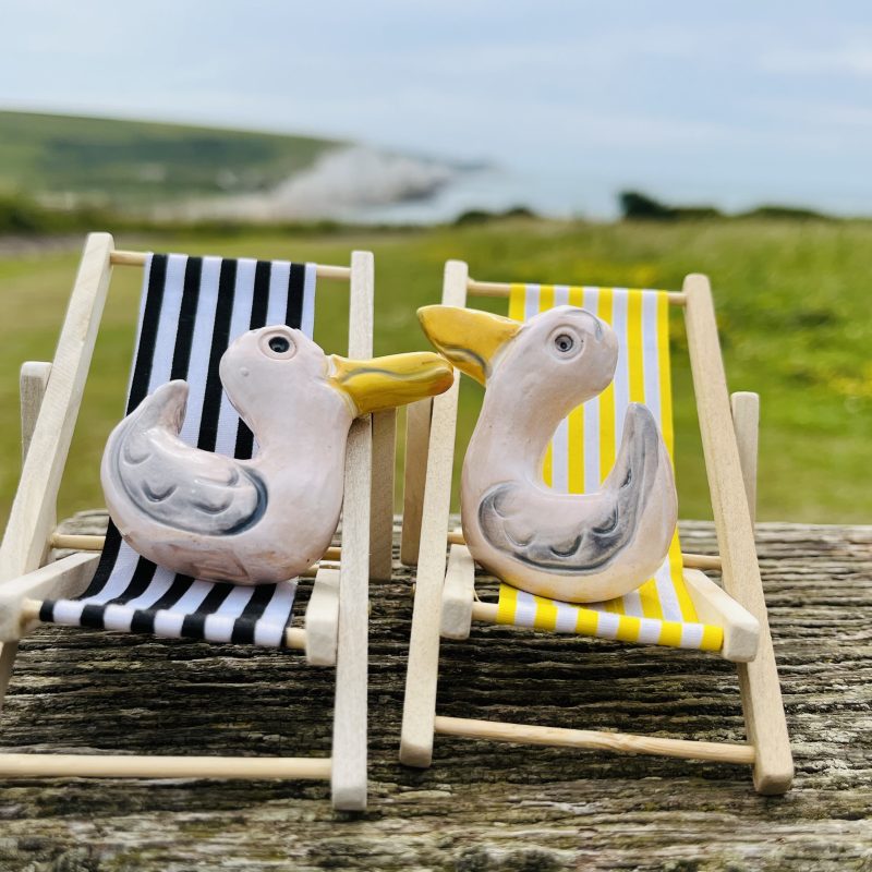 Happy pottery seagulls sitting on their deckchairs.