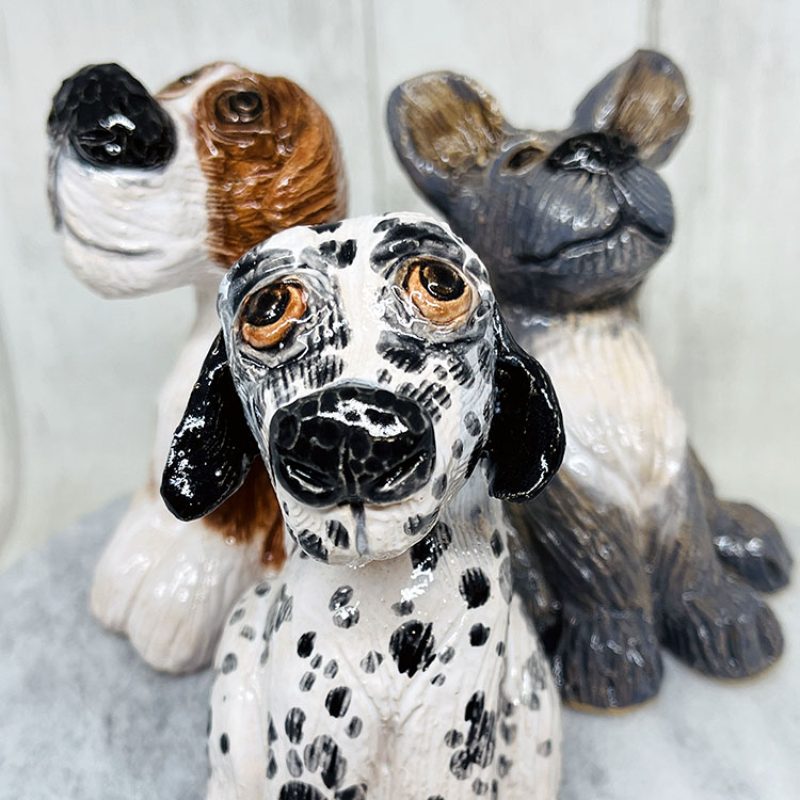 A group of three dogs made out of clay and glazed.