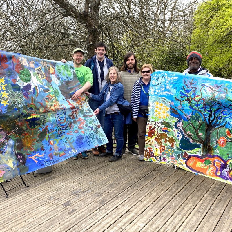 A group of people holding up two large scale paintings