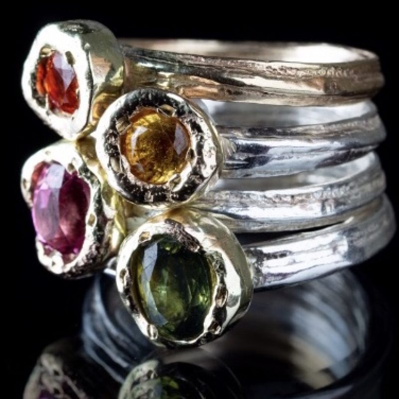 Stack of silver rings with colourful gems